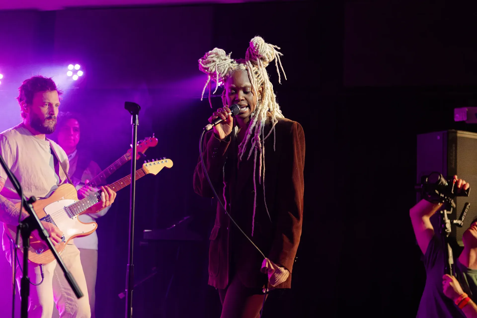 Vocalist with band on stage using an Electro-Voice PL Series vocal microphone